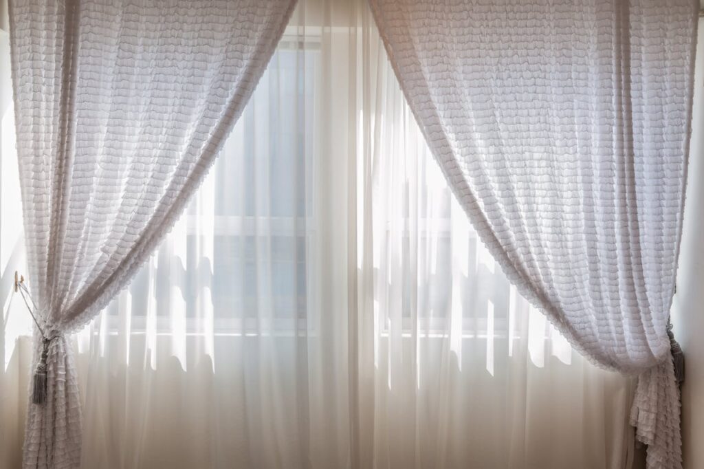 pexels-photo-462197 Sun shining through elegant white curtains in a cozy, modern interior setting.
